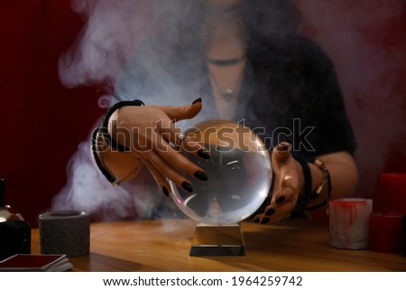 Soothsayer using crystal ball to predict future at table indoors, closeup