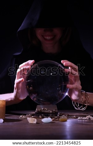 Soothsayer using crystal ball to predict future at table in darkness. Fortune telling