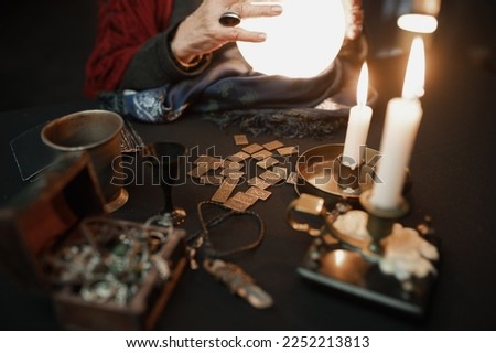 Soothsayer using crystal ball to predict future at table in darkness closeup