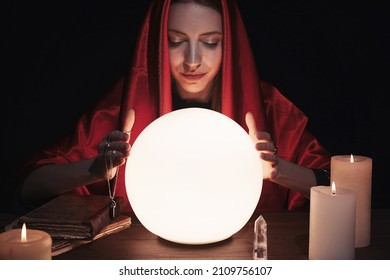 Soothsayer Using Glowing Crystal Ball To Predict Future At Table In Darkness. Fortune Telling