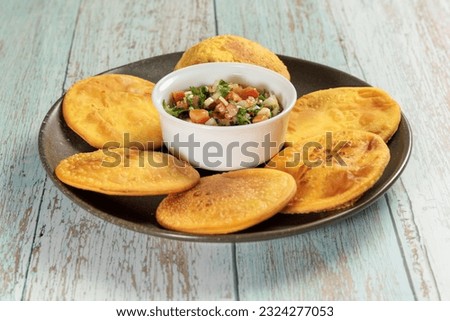 Sopaipillas of pumpkin or squash in round plate on wooden table and bowl with pebre in the center. typical chilean food concept