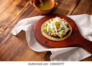 Sopes de Pollo. Aperitivo tradicional mexicano hecho a mano, preparado con masa de maíz frito recubierta de frijoles fritos, salsa verde o roja, lechuga, queso, cebolla y pollo triturado