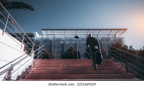 A sophisticated African man executive was captured from behind walking up a large staircase toward an architecturally beautiful and innovative glass made office building - Shutterstock ID 2251669529