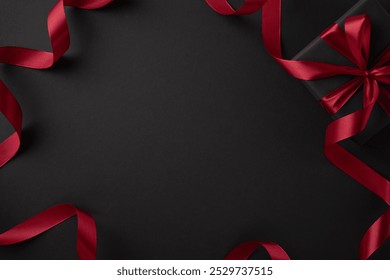 A sophisticated black gift box adorned with a vibrant red ribbon, set against a dark background, symbolizing special celebrations and luxurious presents - Powered by Shutterstock