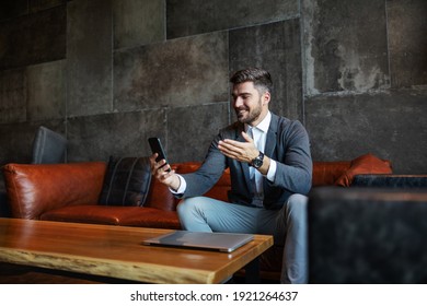 Sophisticated Businessman In Elegant Clothes Sitting In The Hall Of A Hotel And Using The Phone For Video Calls. Technologies, Conference Call, Telecommunications