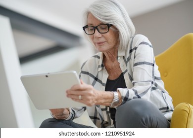 Sophisticated senior woman indoors with tablet                               