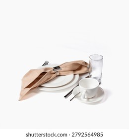 Sophisticated table place setting featuring stacked white ceramic plates, folded beige linen napkin with decorative ring, polished silverware, coffee cup and clear tumbler