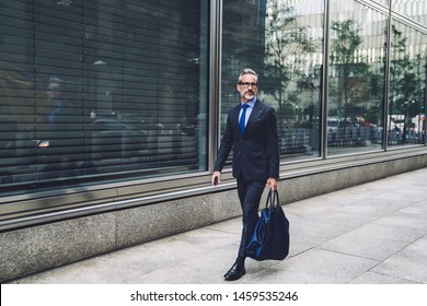 Sophisticated Trendy Middle Aged Senior Man In Elegant Outfit Carrying Bag While Walking Confidently On Street Of New York City 