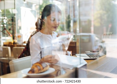 Sophisticated Woman Reading And Drinking Latte In Cafe