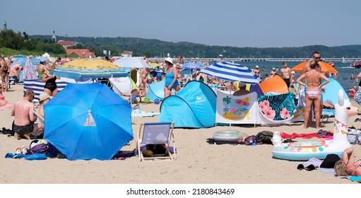 Sopot, Poland - 20 July 2022: People Sunbathe Next To The Screens On The Beach By The Sea.