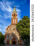 Sopot, Poland - September 7 2022: Saint George church - Kościół Garnizonowy św. Jerzego. Entrance to the church partly lighted in the with big tree next to it. 