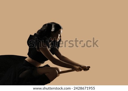 Sorceress witch woman in Halloween costume flying on broom isolated on studio background, Enchanting isolation: Backgrounded brunette woman embraces her mystical sorceress persona.