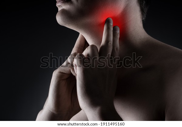 Sore throat, men with pain in neck on\
black background, painful area highlighted in\
red