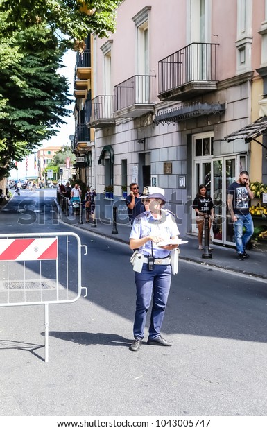 Sorrento, Italy July\
16,2017: Traffic police woman directing cars and pedestrians.\
Sorrento, Italy.