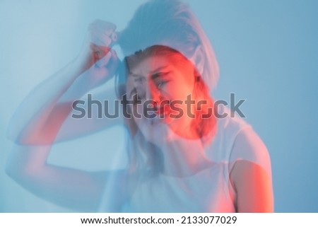 Sorrow grief. Mistake regret. Emotional crisis. Double exposure blur silhouette of hurt desperate crying woman in red neon color light isolated on blue out of focus.