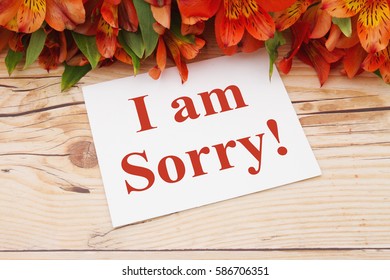 I am sorry message, A bouquet of orange lilies on weathered wood with a greeting card with text I am Sorry