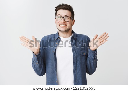 Sorry I messed up. Guilty young and handsome male in glasses and blue shirt raising hands near shoulders, shrugging making awkard smile as apologizing for making mistake over white background Stock photo © 