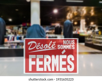 SORRY WE ARE CLOSED lettering in French. Empty trade mall store with closed red sign due to coronavirus pandemic restrictions