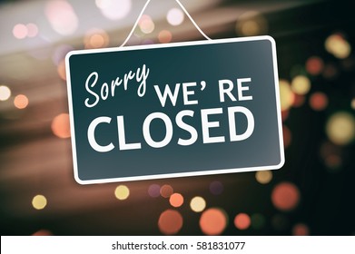 Sorry we are closed sign hanging on a glass storefront - Shutterstock ID 581831077