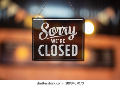 Sorry we're closed sign. grunge image hanging on a glass door.