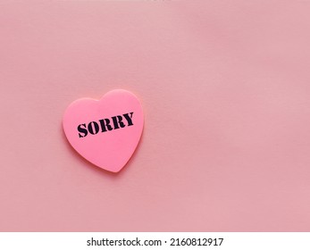 Sorry word written on  pink sticky note in   heart  shape  . Apologizing Concept 