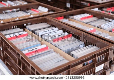 Sorted CD Collection in Crates at Flea Market, ACrates of secondhand music CDs organized alphabetically with handwritten dividers, displayed for sale at an outdoor flea market.lphabetical Order
