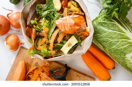 Sorted kitchen waste in paper eco bag on kitchen counter top. Compost-container. Sustainable life style. Vegetable and fruit peels, scraps from food preparation collected in trash-pack for recycling - Shutterstock ID 2093512858