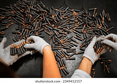 Sorting and selective quality control of weapon cartridges. Hands of the worker in gloves hold cartridges.