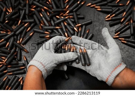 Sorting and selective quality control of weapon cartridges. Hands of the worker in gloves hold cartridges.