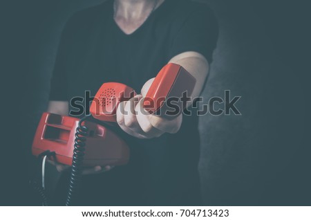 Sos phone or helpline for people in personal crisis - unrecognizable man with old red phone in hand