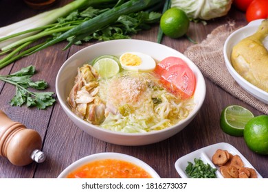 Soto ayam, an Indonesian version of chicken soup, is a clear herbal broth with fresh turmeric and herbs, skinny rice noodles in the bowl. It is served with a boiled egg, celery leaves and chili sauce
