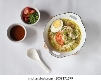 Soto ayam santan is traditional food from Indonesia. Cooked with yellow spices and coconut milk. Served with chicken shredded, chili sauce, tomato, boiled egg and lime slice. Selective focus