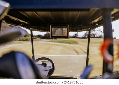 Sotogrande, Spain - January, 23, 2024 - This is a view from the driver's seat of a golf cart, focusing on a GPS screen showing a map of the golf course, with the fairway in the background. - Powered by Shutterstock