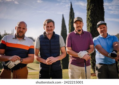 Sotogrante, Spain - January 26, 2024 -four men standing on a golf course, wearing casual golf attire and gloves, holding golf clubs, with trees in the background.