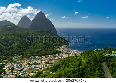 Soufriere, St Lucia from an overlook with the world famous Pitons in the background and beautiful blue Caribbean waters and a partly cloudy day.