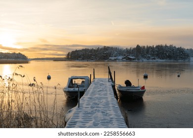 Soukka, Finland - 09.12.22: Winter sunset over the snow-covered islands in the bay. Frozen bay. Pier with boats in the foreground. Winter landscape. Scandinavia. - Powered by Shutterstock