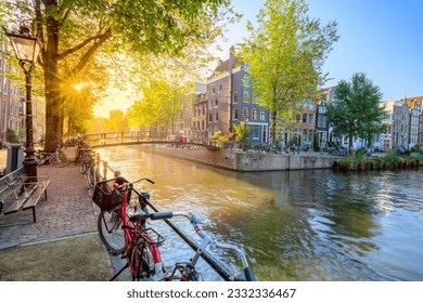 Soul of Amsterdam. Early morning in Amsterdam. Ancient houses, a bridge, traditional bicycles, canals and the sun shines through the trees. Great day in Amsterdam. Holland, Netherlands, Europe. - Powered by Shutterstock