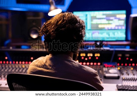 Sound designer tuning audio recordings with faders and buttons on control desk in professional music studio, mixing and mastering tracks for a new album. Adjusting volume levels with equalizer.