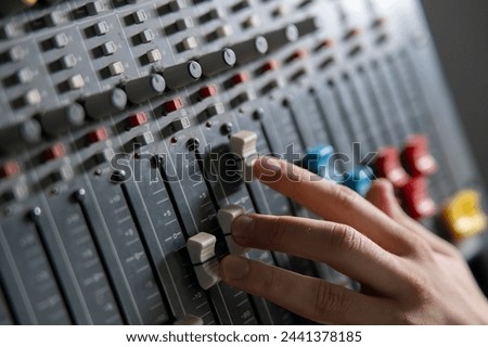 Sound Engineer Adjusting Faders on a Mixing Console During Studio Session
