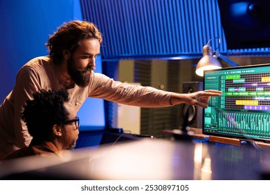 Sound engineer collaborating with singer to edit sounds and compose songs in control room at professional studio, recording for an album. Audio technician operating mixer and controller board.