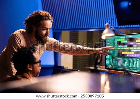 Sound engineer collaborating with singer to edit sounds and compose songs in control room at professional studio, recording for an album. Audio technician operating mixer and controller board.