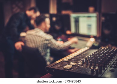 Sound engineer and producer working together at mixing panel in the boutique recording studio. - Shutterstock ID 373495843