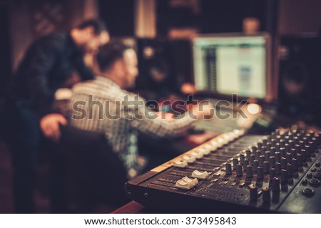 Sound engineer and producer working together at mixing panel in the boutique recording studio.