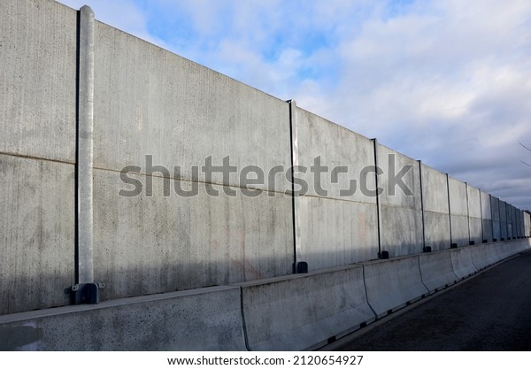 soundproof wall made of concrete porous ribbed\
material. fence of gray blocks embedded in metal beams, on street.\
road traffic noise  garden and residential area. protection of\
Jerusalem, rocket