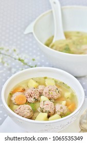soup with meatballs in a white bowl on the background of a gray tablecloth in polka dots. light soup with pork meatballs. French style dishes.