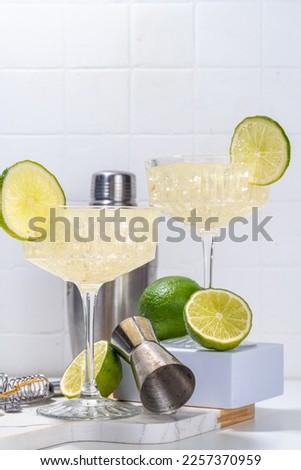 Sour alcoholic lime gin gimlet drink. Lemonade martini alcohol boozy cocktail garnished with lime, white background copy space