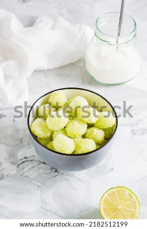 Sour candy grapes in a bowl, lime and sugar for cooking on the table. Social media candy trend. Vertical view