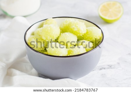 Sour candy grapes in a bowl, lime and sugar for cooking on the table. Social media candy trend. Close-up