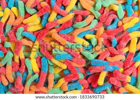Sour candy gummy worms close up background. Covered in granulated sugar. Flat lay top view from above.