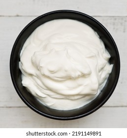 Sour Cream In A Black Bowl On Wooden Background